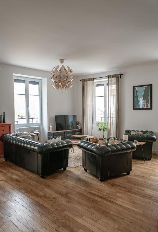 a living room with leather furniture and a chandelier at Grande Maison Vichy - Maison ou Appartements en Centre ville in Vichy