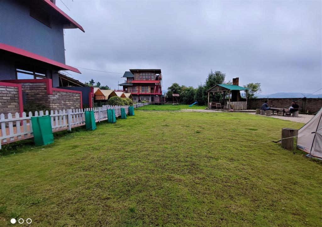 a yard with a white fence and a playground at Silver Brook Resort Mylliem Upper Shillong in Shillong