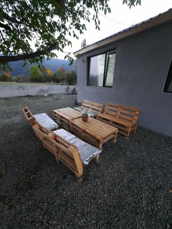 duas cadeiras de madeira e uma mesa em frente a uma casa em Kesi’s House em Borjomi