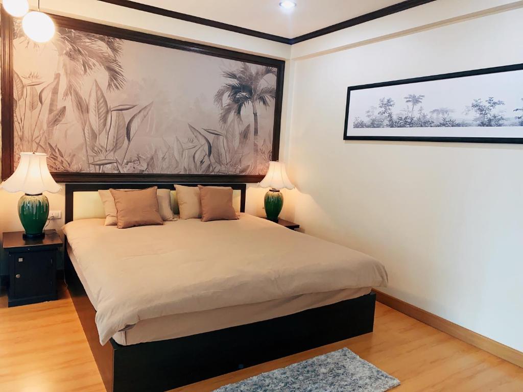 a bedroom with a bed with two lamps and a painting at October Hostel ChiangMai in Chiang Mai