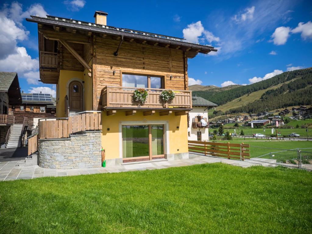 a house with a balcony and a green lawn at Chalet 4 Stagioni in Livigno