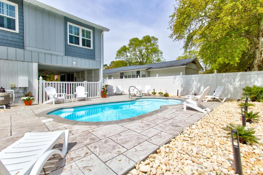 a backyard with a pool and chairs and a house at Ocean Isle Hidden Retreat in Ocean Isle Beach