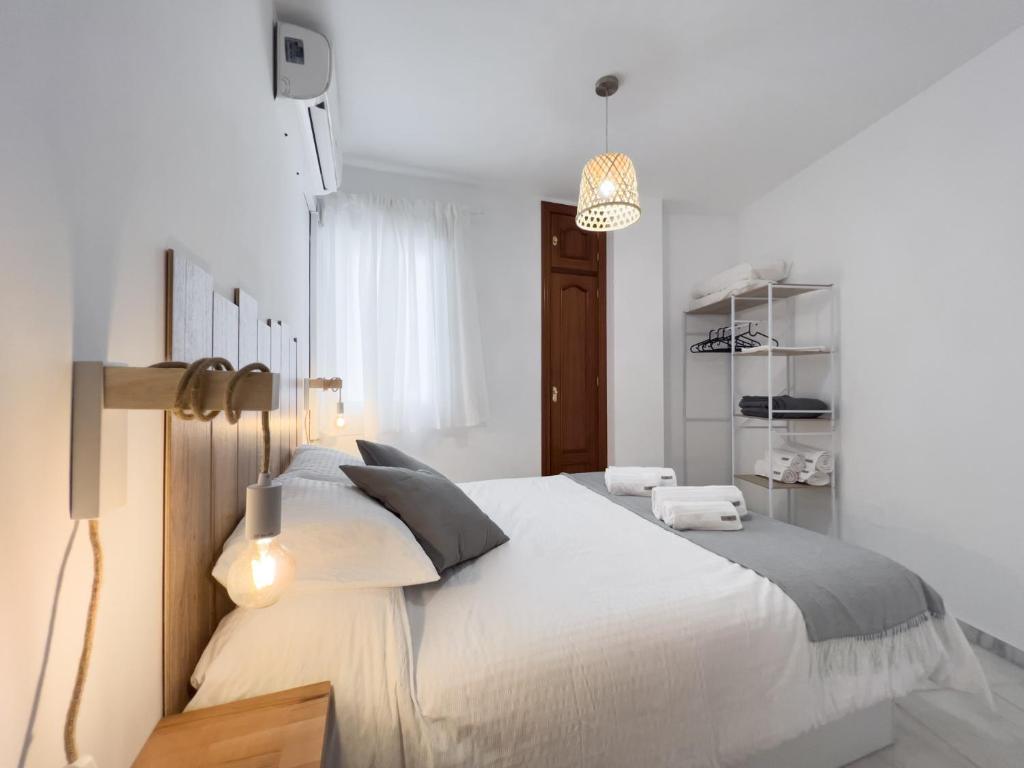 ein weißes Schlafzimmer mit einem großen Bett und einem Kronleuchter in der Unterkunft 1 Mijas Apartment in Mijas