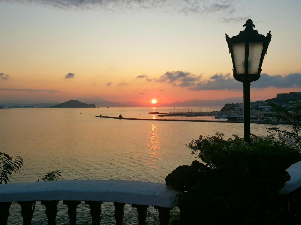 einen Sonnenuntergang über dem Wasser mit Straßenlicht in der Unterkunft Summer Paradise in Procida