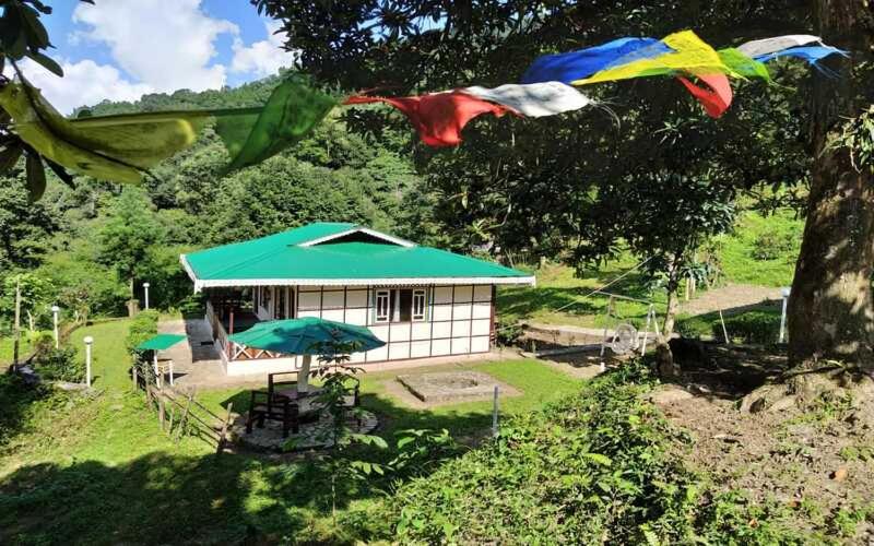 a small white house with a green roof at The Nettle and Fern Farmstay in Pelling