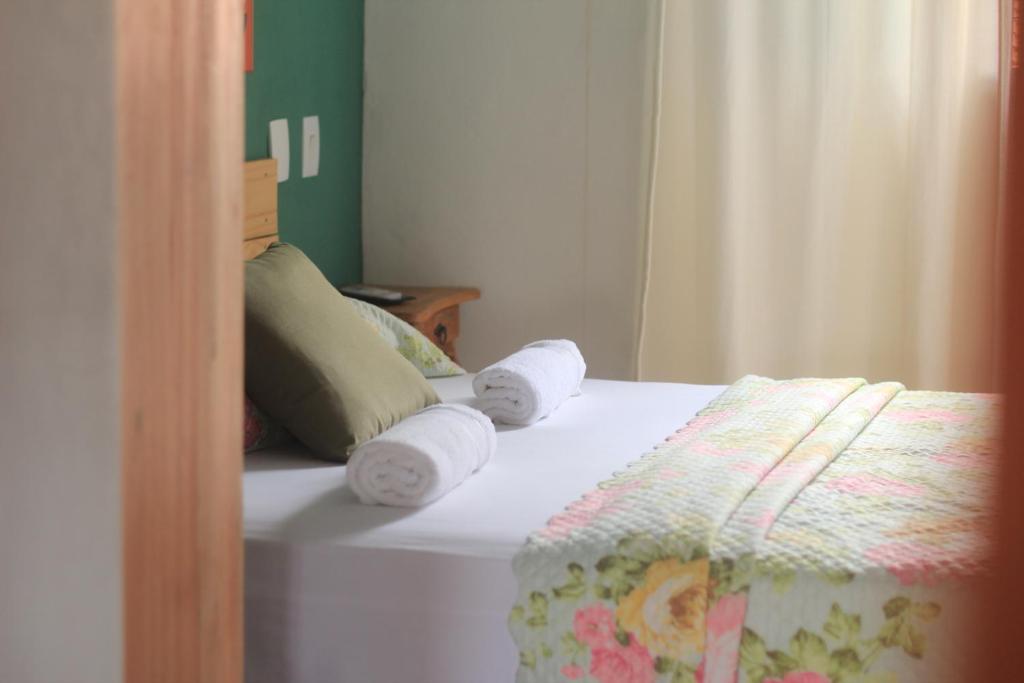 Una cama con dos rollos de toallas. en Suítes Tia Olívia, en Pirenópolis