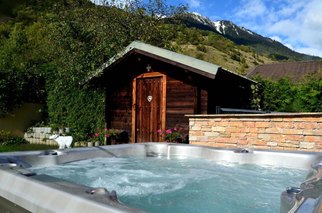 a large hot tub in front of a building at Grand chalet avec Jacuzzi et jardin clos, proche Paradiski in Aime-La Plagne