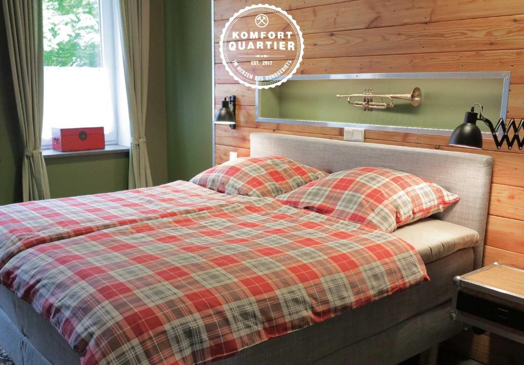 a bed with a plaid blanket and two pillows at Komfortquartier in Oberhausen