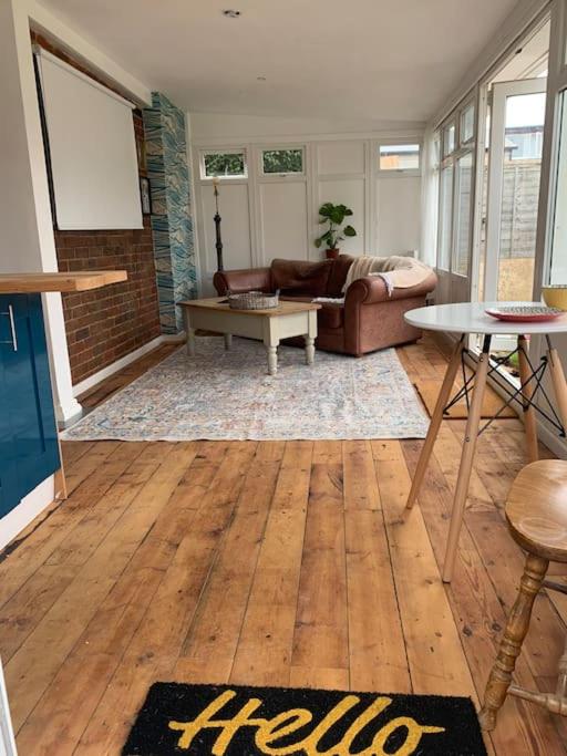 a living room with a couch and a table at Seaside 1 Bed Studio Conversion in Selsey