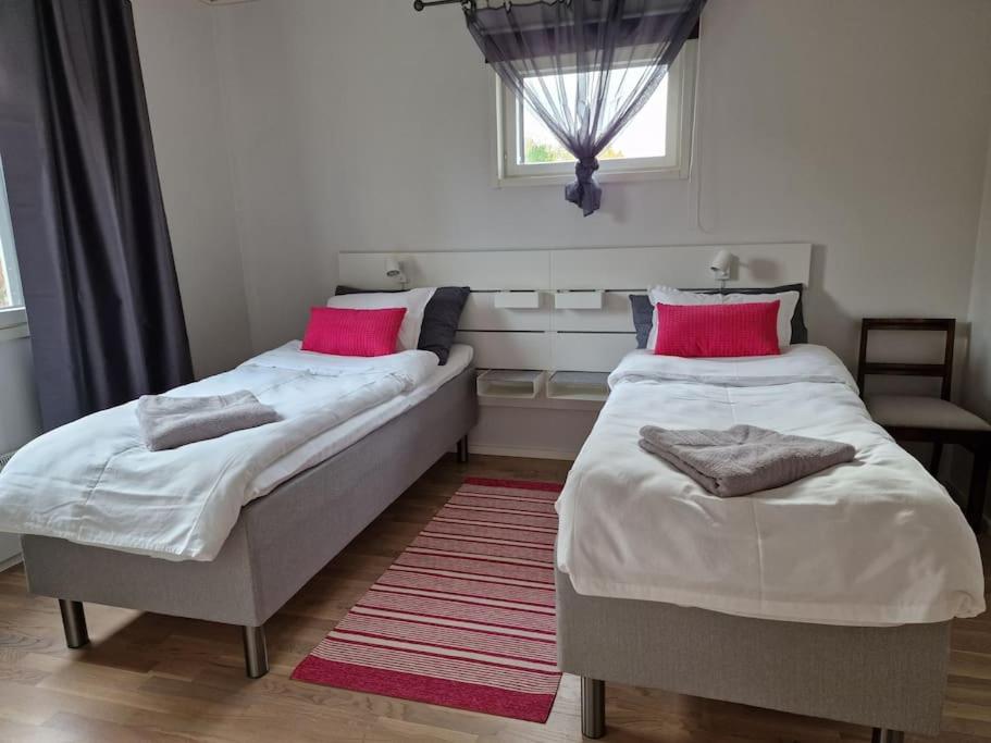 2 camas en una habitación pequeña con almohadas rosas en Villa Silve, yhden makuuhuoneen omakotitalo., en Lohja