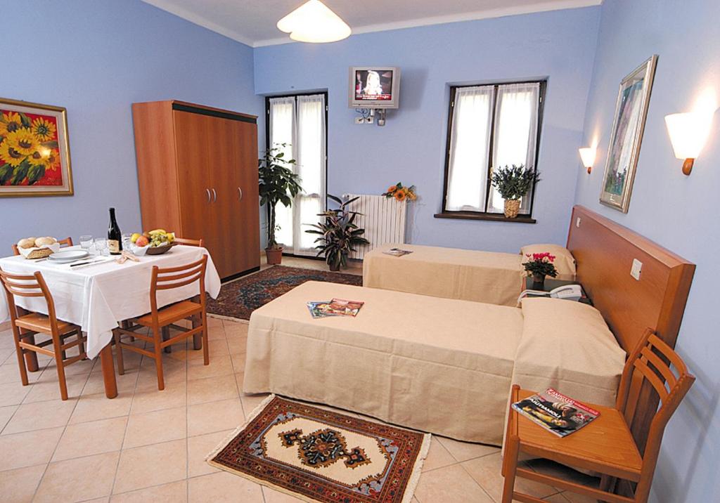 a room with two beds and a table and chairs at Casa Vacanze Provenzale in Torre Pellice