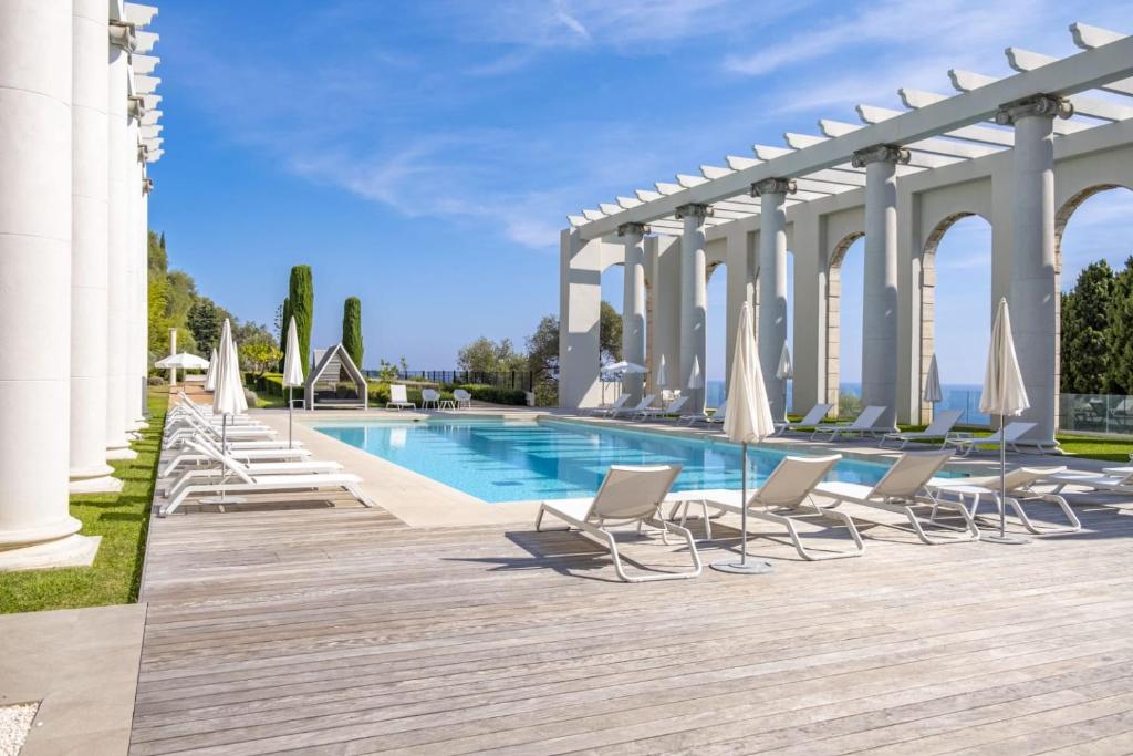 une rangée de chaises et une piscine avec parasols dans l'établissement Superbe appartement Cap de nice, à Nice