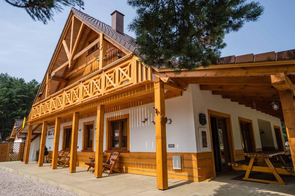 a large wooden house with a large porch at Swornegacie Villa nad Zbrzycą in Wielkie Zanie