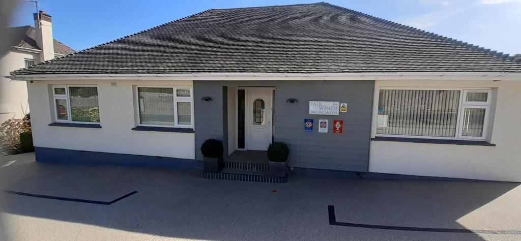 a small white house with a door in a driveway at Fair Winds Guest House in Brixham