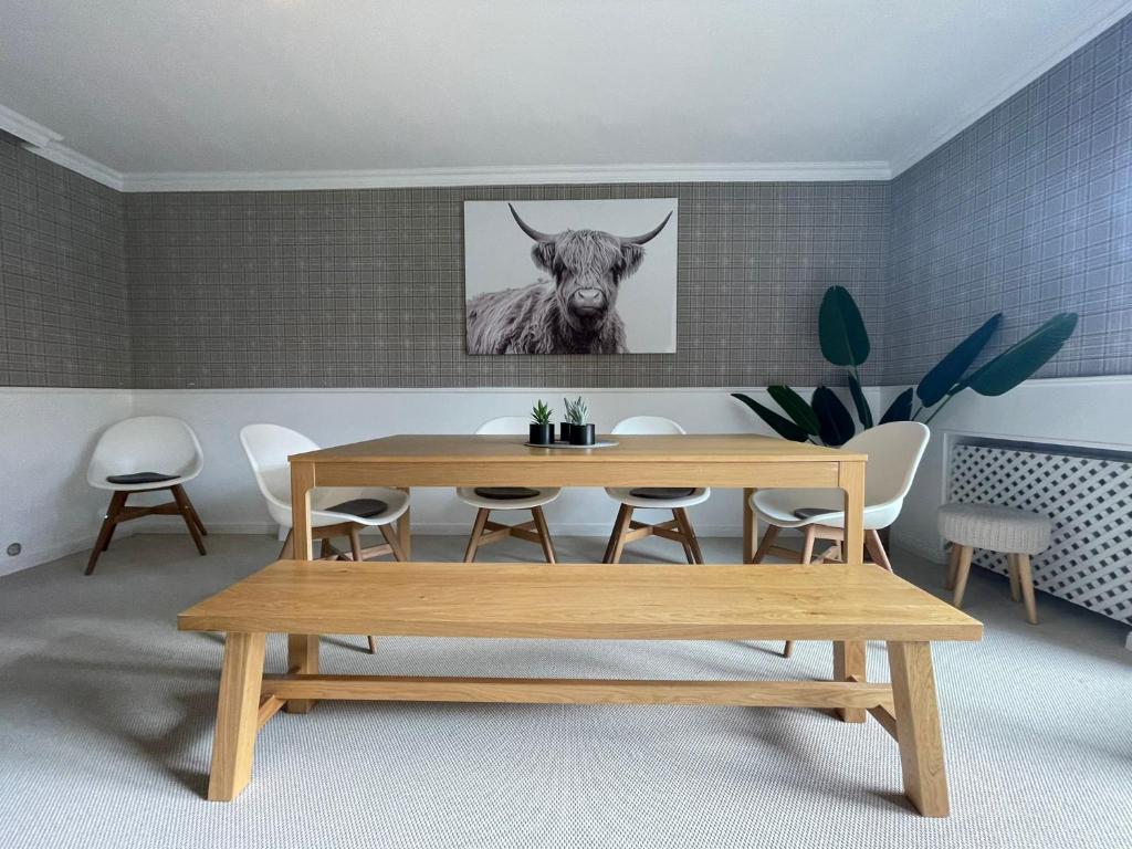 a dining room with a table and a cow picture on the wall at Hochfeld City Apartment in Tegernsee