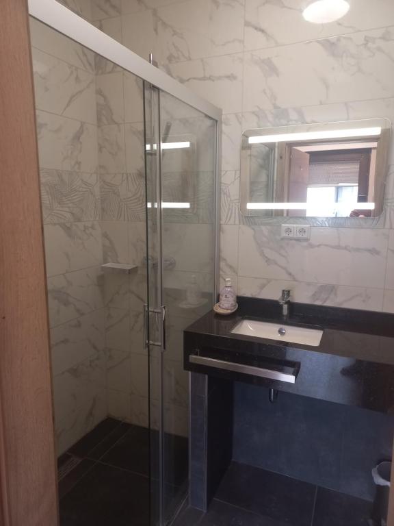 uma casa de banho com uma cabina de duche em vidro e um lavatório. em Cafe Hotel centrum em Bruchsal