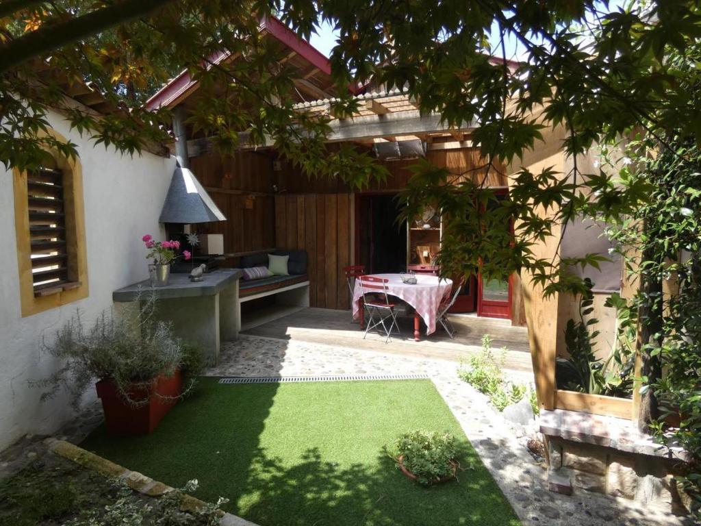 um quintal com uma mesa e relva verde em Gîte l'Atelier Bois em Gaillères