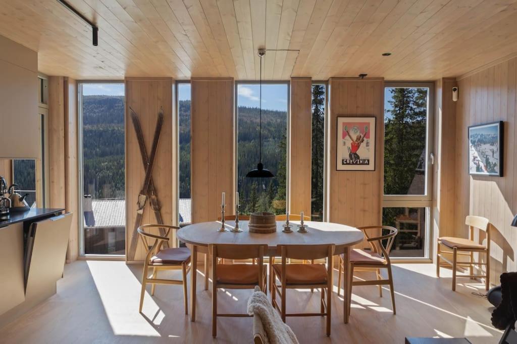 ein Esszimmer mit einem Tisch, Stühlen und Fenstern in der Unterkunft Ny leilighet på Kvitfjell Vest. Ski inn/ut in Favang