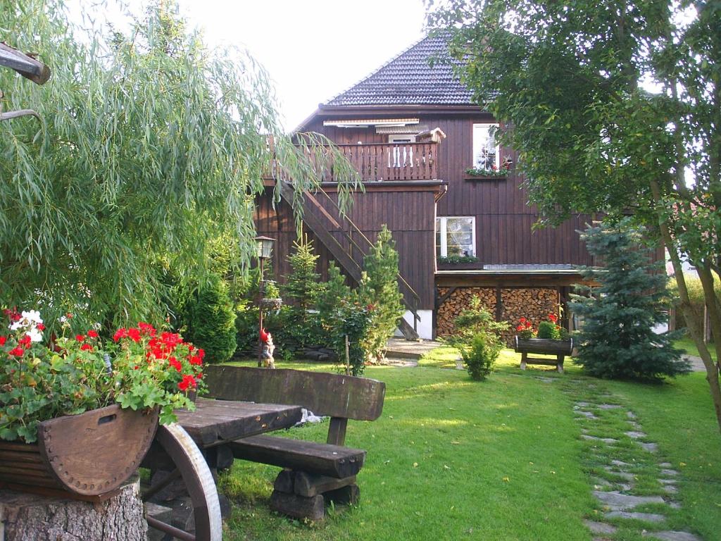un giardino con una casa in legno con panchina e fiori di Ferienwohnung Lachmann a Benneckenstein