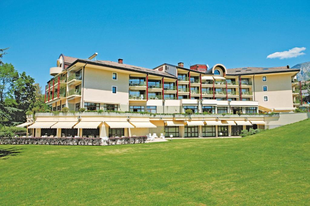 un gran hotel con césped delante en Hotel *** & Spa Vacances Bleues Villa Marlioz, en Aix-les-Bains