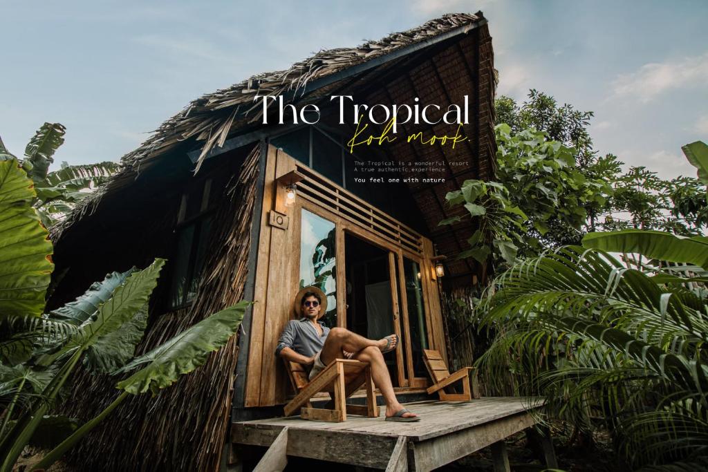 a woman sitting in a chair outside of a tiny house at The Tropical Koh Mook in Ko Mook