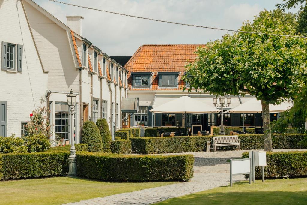 a courtyard with a building and a table and chairs at Auberge du Pêcheur in Sint-Martens-Latem