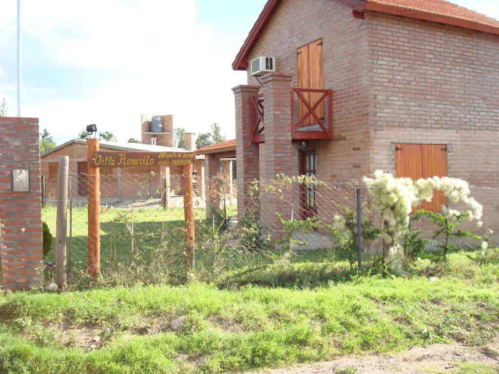 una valla delante de una casa con un cartel en Cabañas Rosarito en Villa Larca