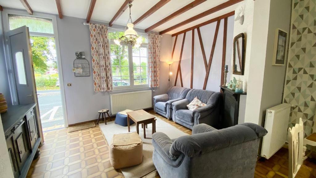 - un salon avec deux canapés bleus et une télévision dans l'établissement Les Sauterelles, à Saint-Valery-sur-Somme