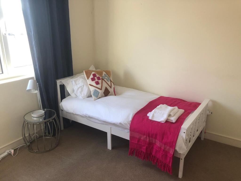 a small bedroom with a white bed with a pink blanket at Luxury Town Centre Property with parking in Cheltenham