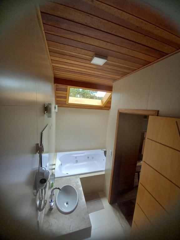 a bathroom with a sink and a bath tub at Chalé Caminho da Fonte in Monte Verde