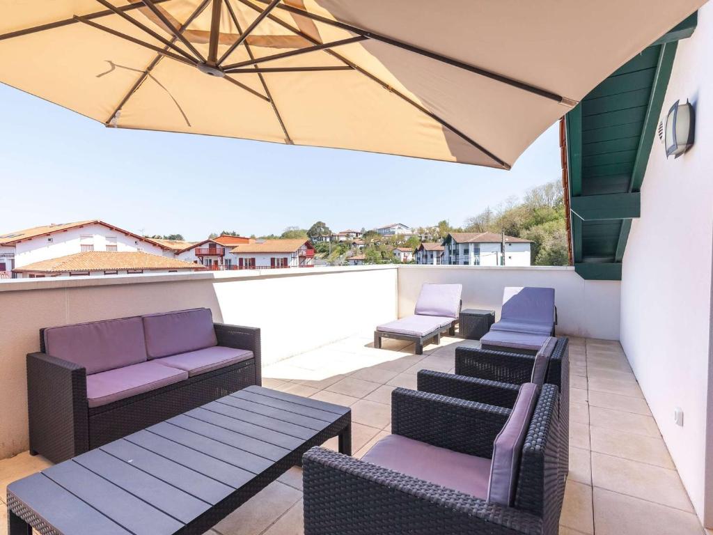 a patio with chairs and tables and an umbrella at Appartement moderne à Hendaye, 400m de la plage, terrasse, parking et WiFi inclus - FR-1-2-371 in Hendaye