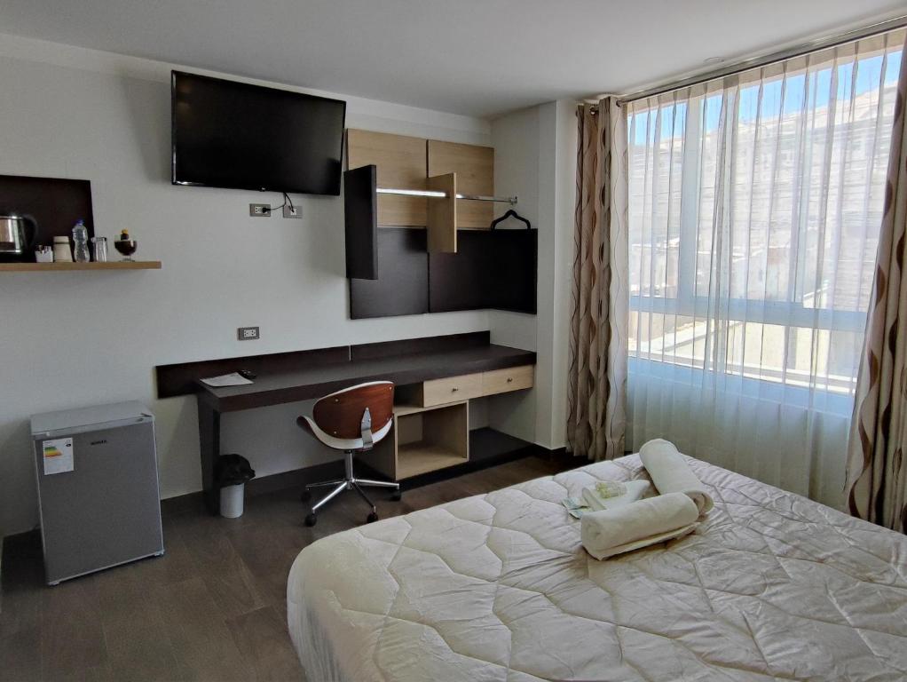 um quarto de hotel com uma cama, uma secretária e uma televisão em Tierra del Sol Centro em Moquegua