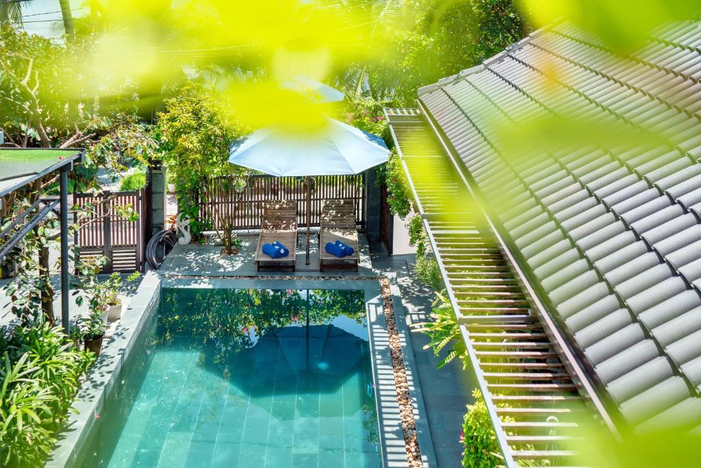 an overhead view of a swimming pool with an umbrella at Sands River Hoi An Villa in Hoi An