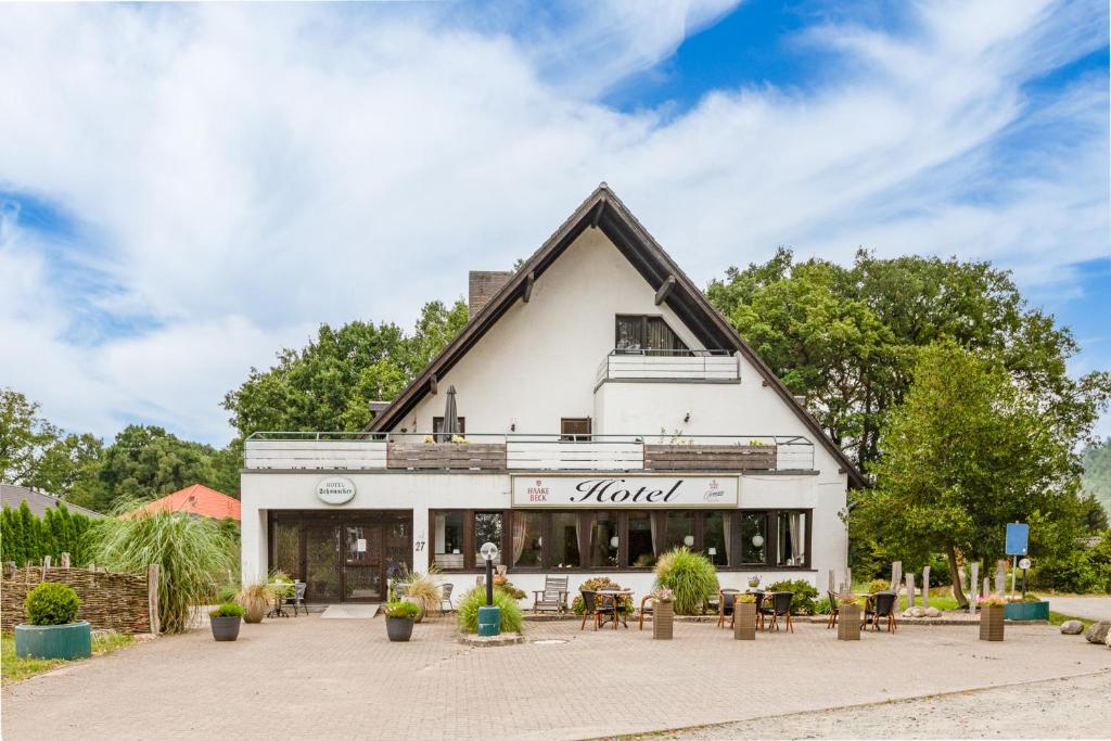 ein großes weißes Gebäude mit Tischen und Stühlen davor in der Unterkunft Hotel Schomacker in Lilienthal