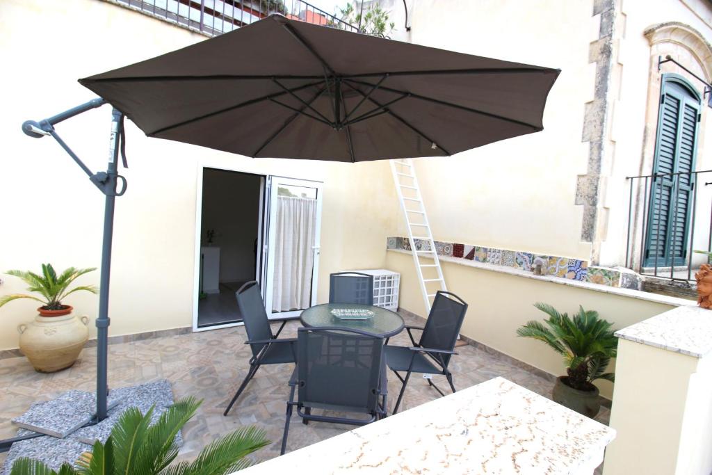 un patio con mesa, sillas y sombrilla en Modica Balcony en Modica