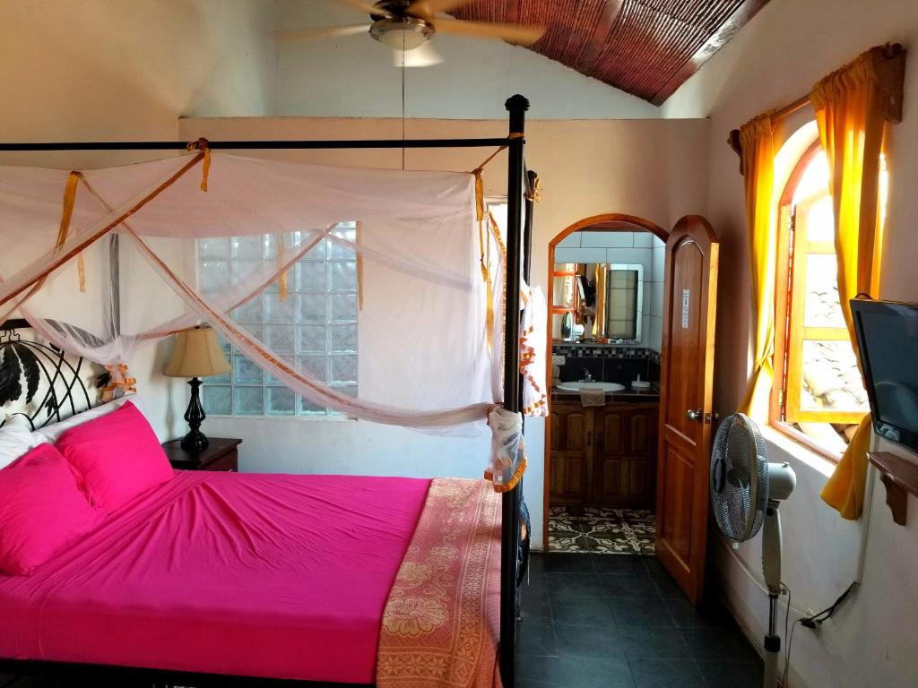 Schlafzimmer mit einem Bett mit rosa Tagesdecke in der Unterkunft Casa del Agua in Granada