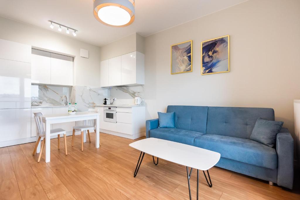 a living room with a blue couch and a table at Wola Lush Apartment in Warsaw