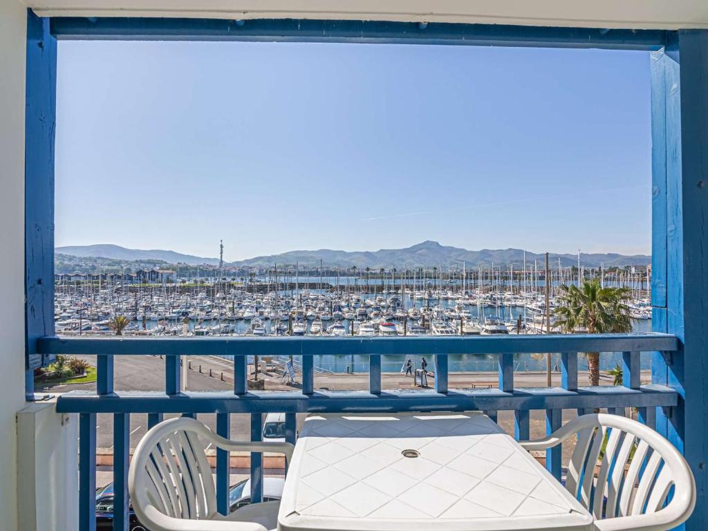 un balcon avec une table et des chaises et un port de plaisance dans l'établissement Appartement rustique avec piscine près du port et plage - FR-1-2-284, à Hendaye