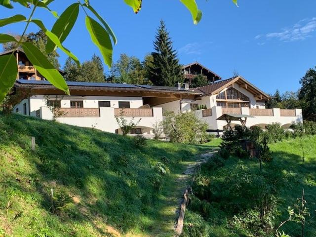a house on a grassy hill with a pathway leading to it at Alpenvilla Berchtesgaden Appartements in Berchtesgaden