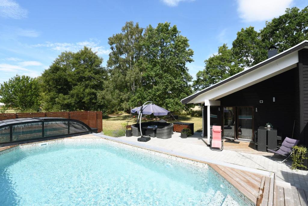 a swimming pool in front of a house with a patio at Nice holiday home with outdoor pool in Lottorp, Oland in Löttorp