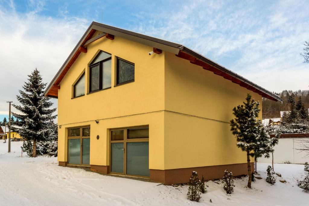 una casa amarilla con techo rojo en la nieve en Apartmán Elizabeth, en Krahule