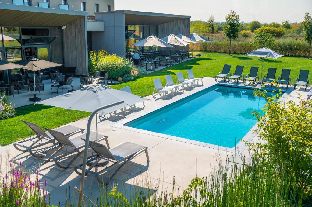 uma piscina com espreguiçadeiras e um resort em Best Western Plus Hotel & Restaurant Les Humanistes Colmar Nord em Sélestat