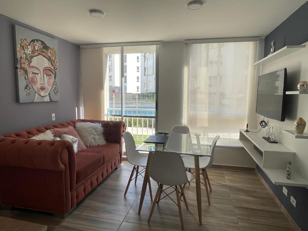 Apartahotel في إباغويه: غرفة معيشة مع أريكة حمراء وطاولة