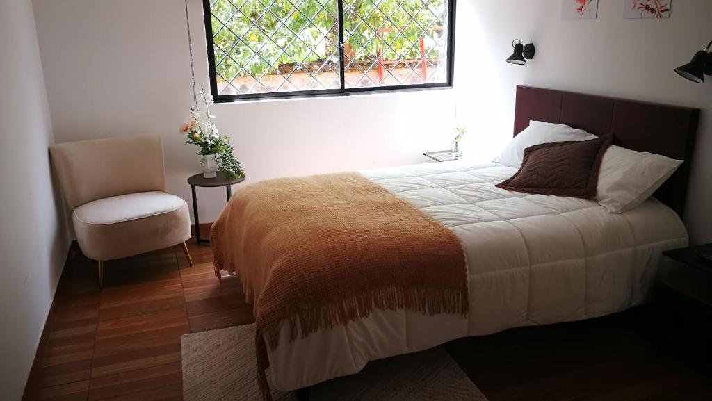 a bedroom with a bed and a chair and a window at Chapelet Hostal in Tababela