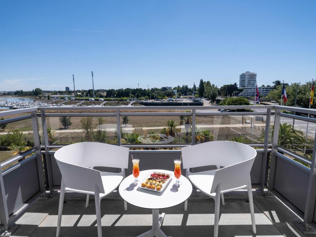 a table and chairs on a balcony with a plate of food at Westotel Le Pouliguen in Le Pouliguen