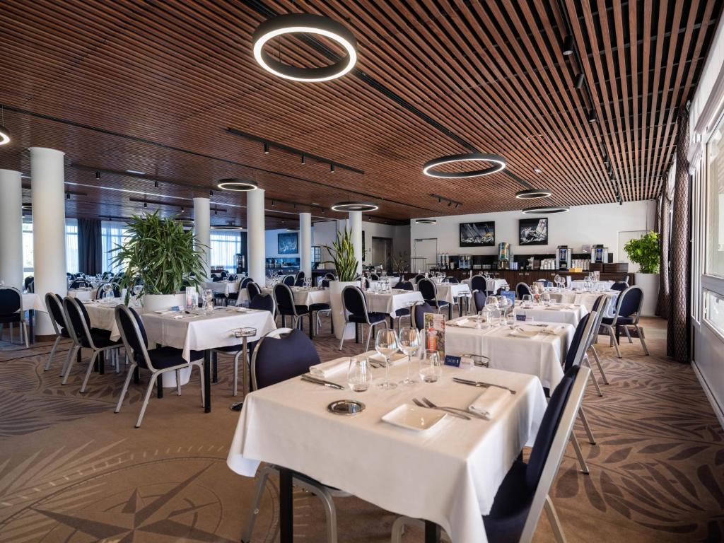 a dining room with white tables and chairs at Westotel Le Pouliguen in Le Pouliguen