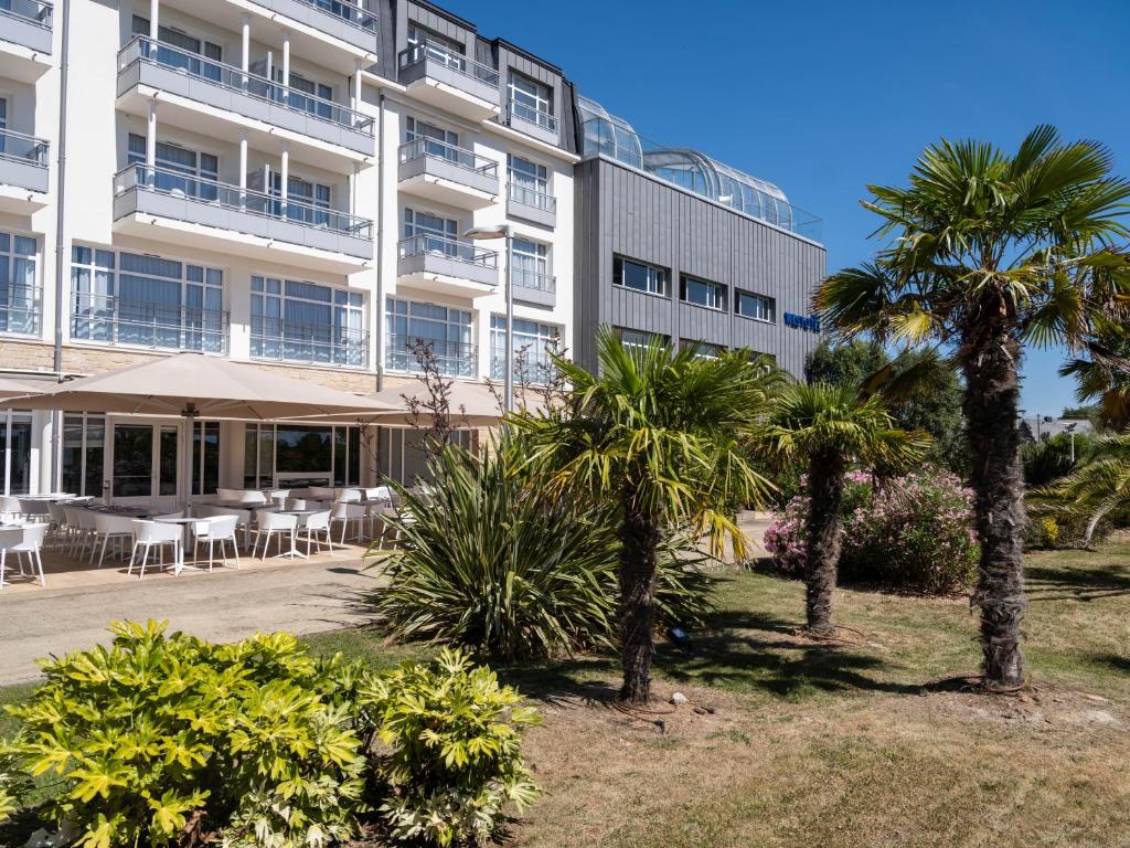 a building with palm trees in front of it at Westotel Le Pouliguen in Le Pouliguen