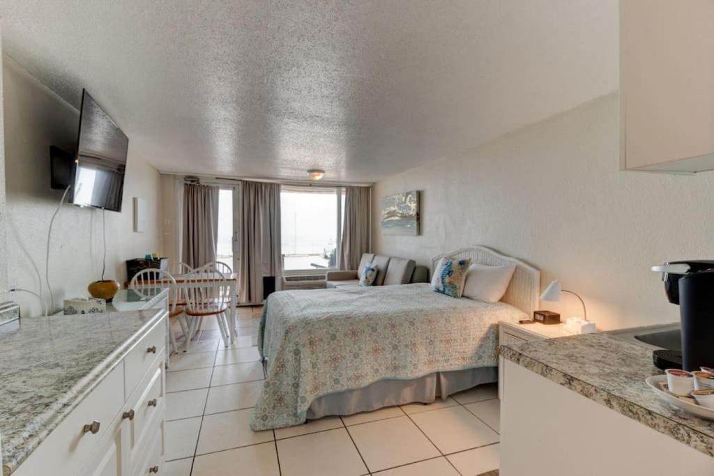 een slaapkamer met een bed in een kamer met een keuken bij Hidden Treasure oceanfront studio with pool in Daytona Beach