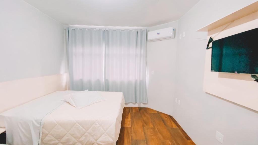Kleines weißes Zimmer mit einem Bett und einem Fenster in der Unterkunft Nacional Hotel Coral in Lages