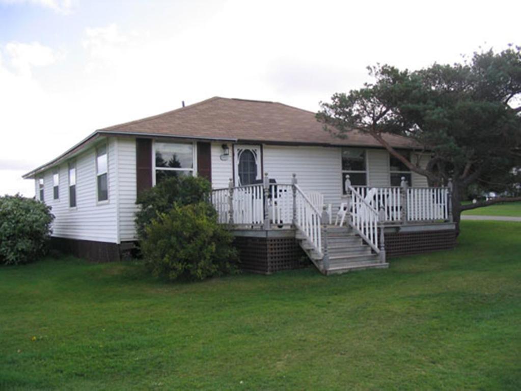 a small white house with a porch and stairs at Shining Waters - Ingleside Cottages in Cavendish